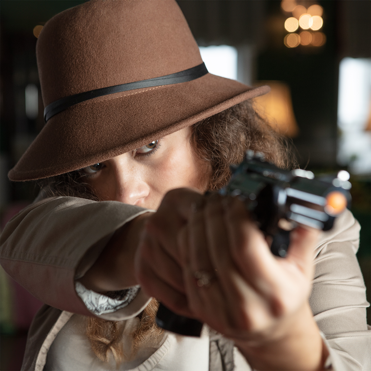 A person in a fedora holding a gun.