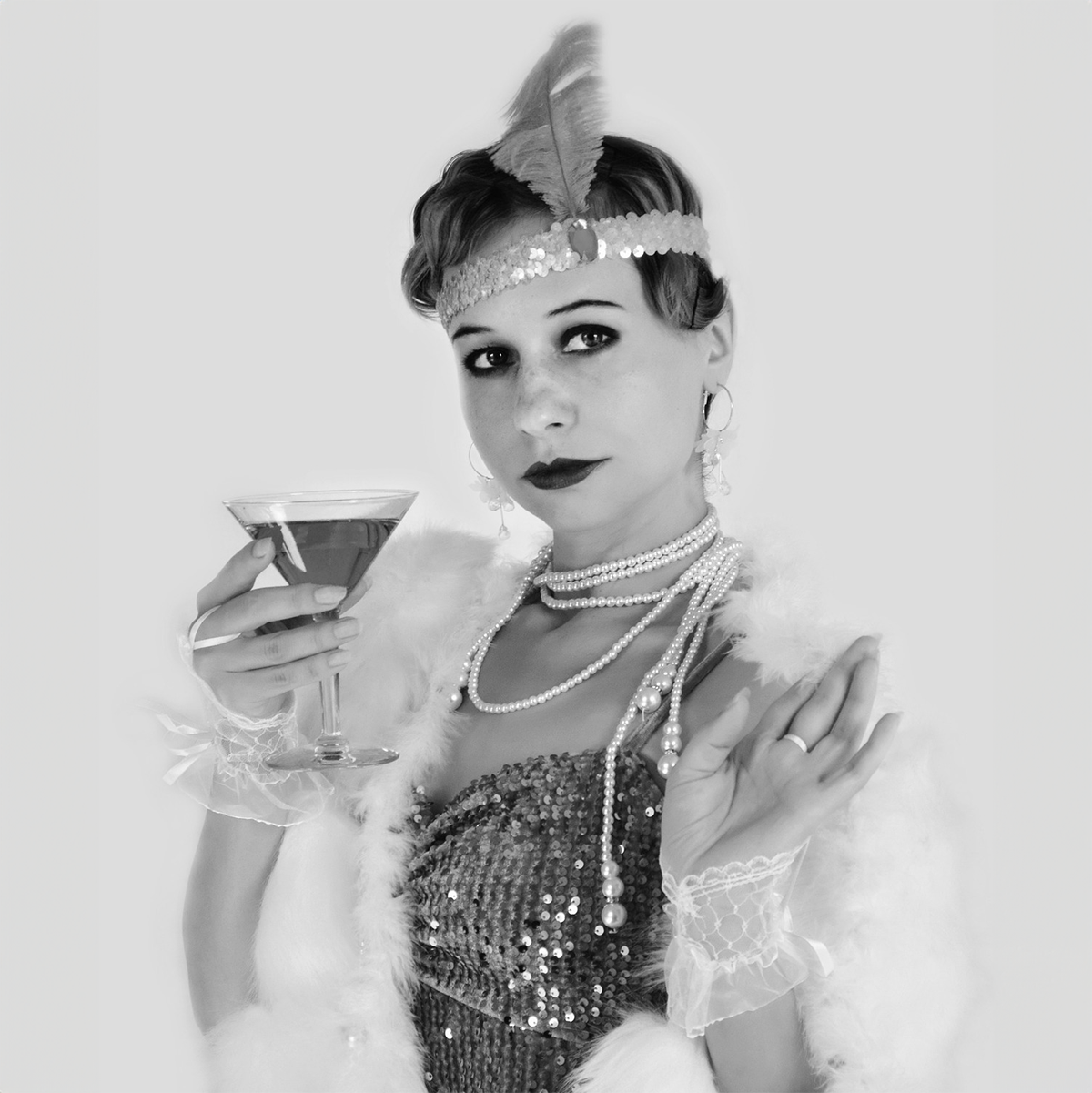 A black and white photo of a person dressed like a flapper and holding a martini